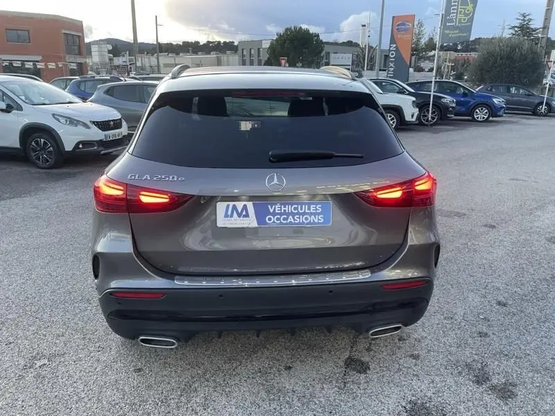 Vue arrière d'un Mercedes GLA 250 e AMG Line gris foncé métal avec feux allumés sur un parking extérieur.
