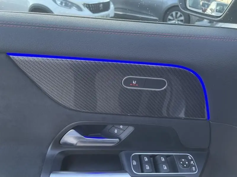 Détail de la porte côté gauche d’un Mercedes GLA 250 e AMG Line 2025 en gris foncé métal avec éclairage d’ambiance bleu.