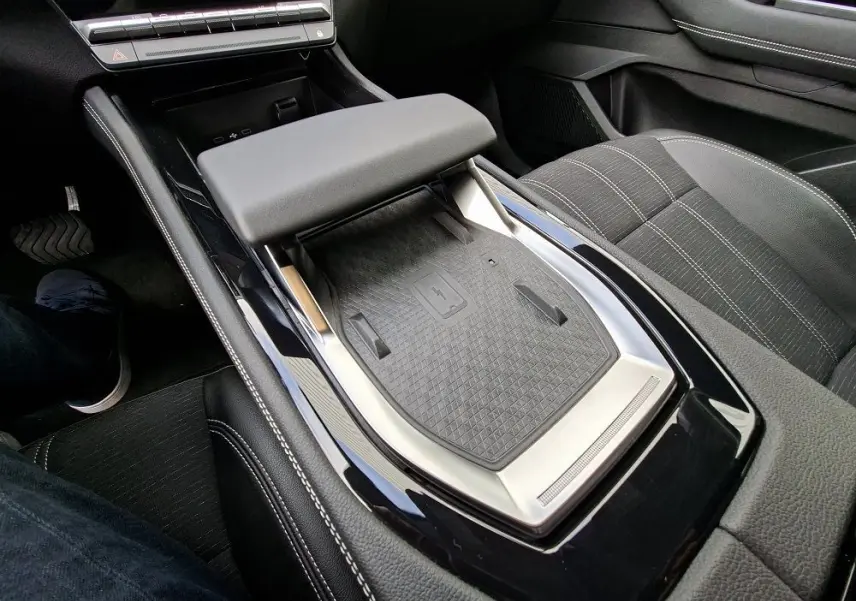 Vue intérieure rapprochée du coffre central et de la console noire brillante du Renault Austral gris schiste, avec accoudoir rembourré.