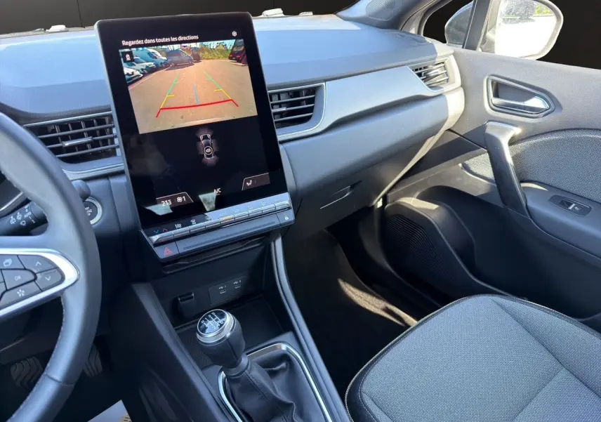Vue intérieure côté passager du tableau de bord et console centrale du Renault Captur TCe 90 Techno 2024 avec écran tactile vertical et boîte manuelle.