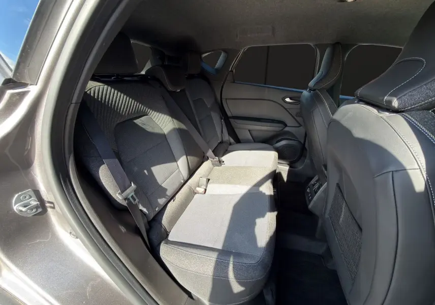 Vue intérieure côté gauche des sièges arrière gris tissu et cuir du Renault Captur TCe 90 Techno 2024 avec ceinture de sécurité visible.