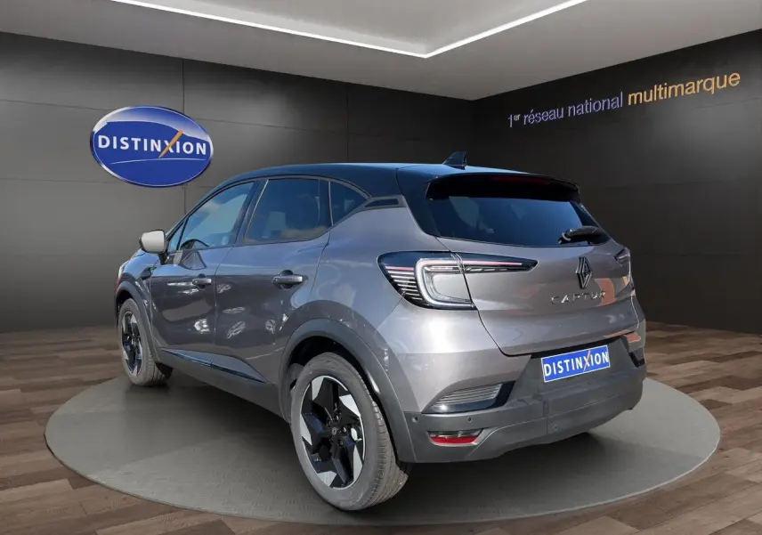 Vue 3/4 arrière droite du Renault Captur TCE 90 Techno 2024 gris Cassiopée avec toit noir et jantes bicolores.
