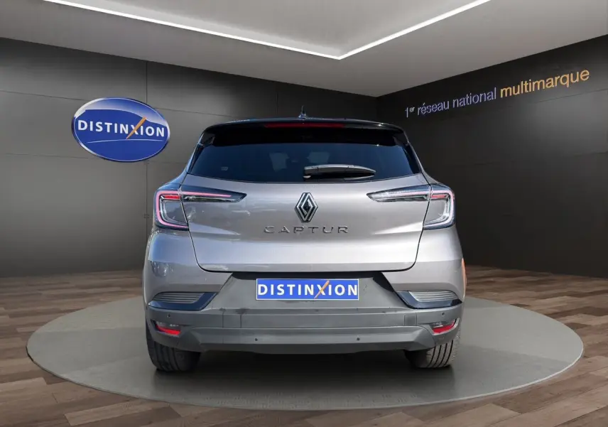 Vue arrière du Renault Captur TCE 90 Techno 2024 en gris Cassiopée avec toit noir, sur plateau en showroom.