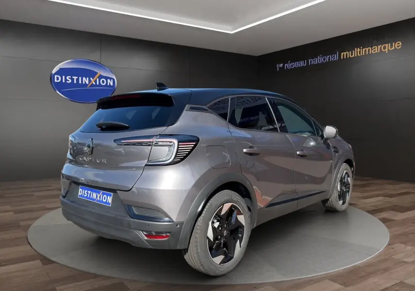 Vue 3/4 arrière droite d’un Renault Captur 2024 gris Cassiopée avec toit noir et jantes noires bicolores.
