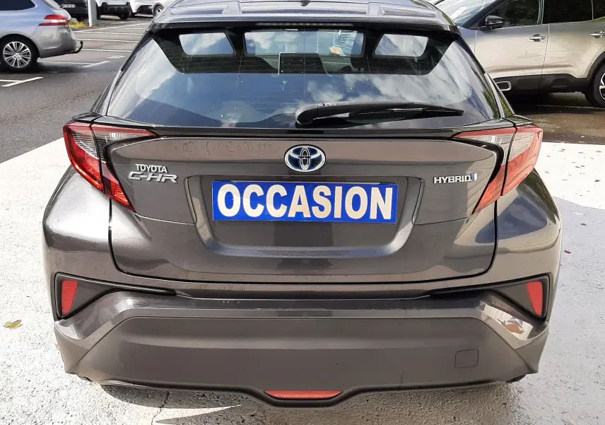 Vue arrière d'un Toyota C-HR gris atlas métal avec plaque "OCCASION" et feux arrière anguleux distinctifs.