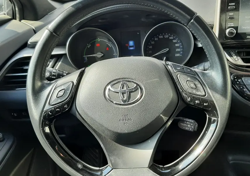 Vue rapprochée du volant noir du Toyota C-HR 1.8 Hybrid 2021, avec commandes intégrées et tableau de bord visible.