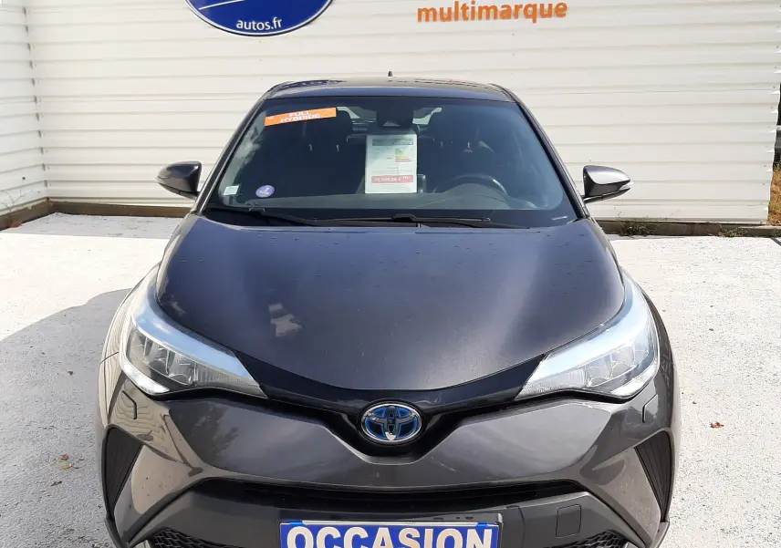 Vue frontale d'un Toyota C-HR 1.8 Hybrid gris atlas métal, avec plaque "OCCASION" et pare-chocs au design anguleux.