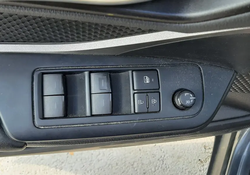 Gros plan sur les commandes de lève-vitres et réglage des rétroviseurs côté conducteur du Toyota C-HR gris Atlas Hybrid 2021.