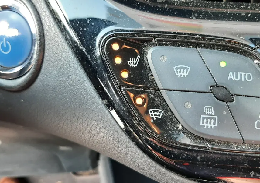 Gros plan sur les commandes de chauffage et dégivrage du tableau de bord du Toyota C-HR gris atlas métal, avec voyants allumés.