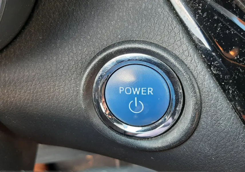 Bouton bleu Power en gros plan sur le tableau de bord intérieur du Toyota C-HR 1.8 Hybrid 2021 gris atlas metal.
