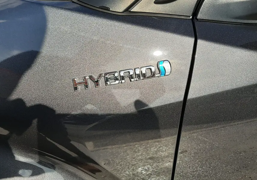 Gros plan sur l’inscription "HYBRID" sur la porte avant gauche d’un Toyota C-HR gris atlas métallisé.