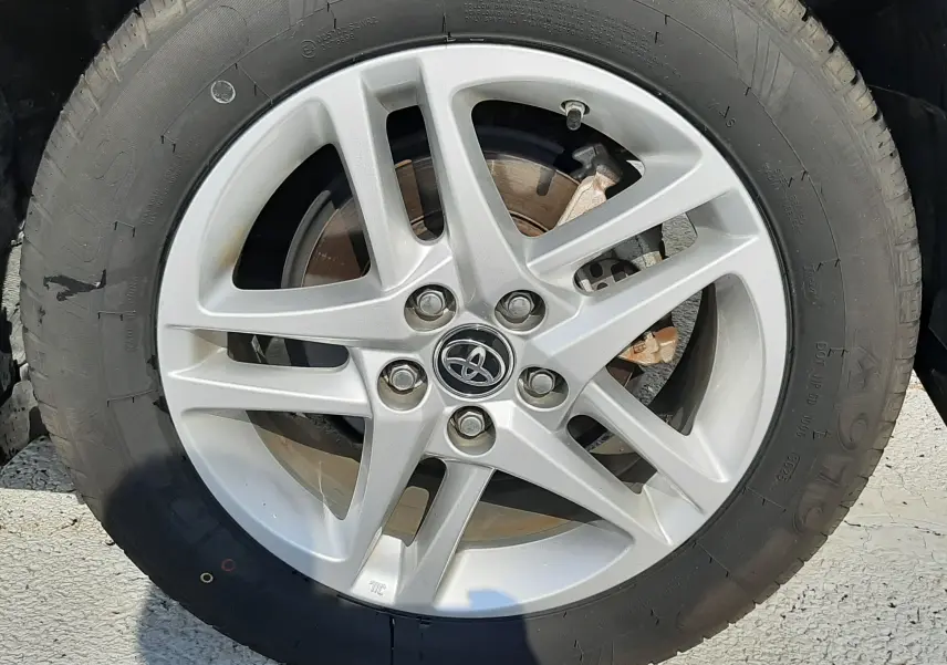 Gros plan sur la jante alliage argentée avec logo Toyota, pneu noir monté sur Toyota C-HR gris atlas metal.