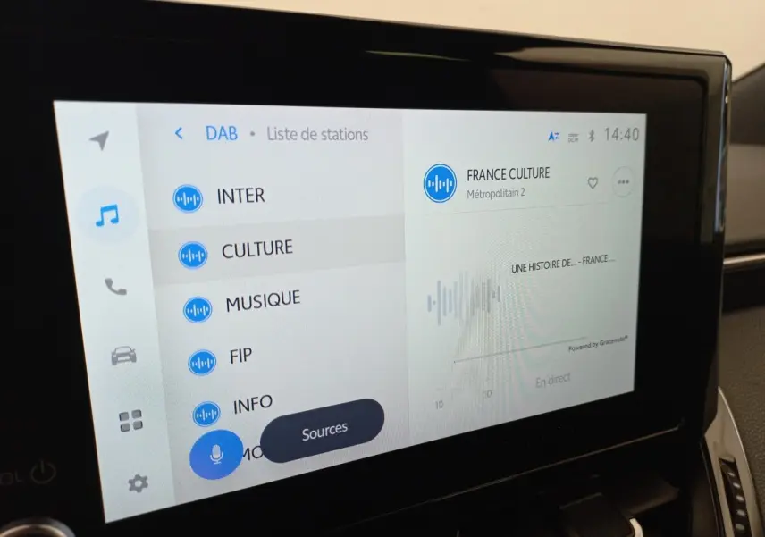Écran tactile central de la Toyota Corolla hybride 2022 affichant la liste des stations radio en intérieur.