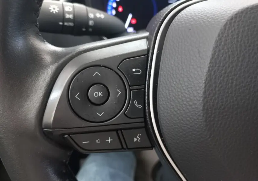 Gros plan sur les commandes multifonctions du volant cuir côté gauche de la Toyota Corolla hybride 2022.