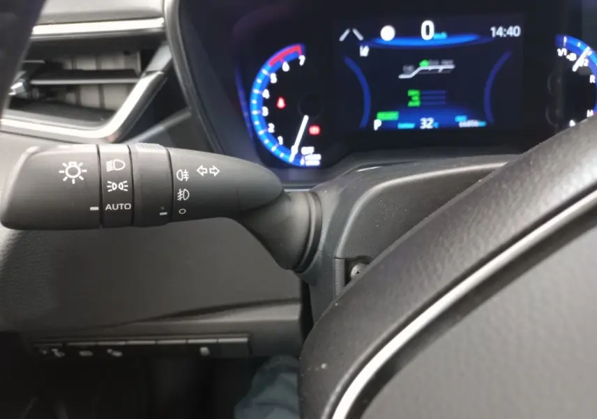 Vue rapprochée du commodo gauche et du tableau de bord numérique bleu de la Toyota Corolla hybride 2022.