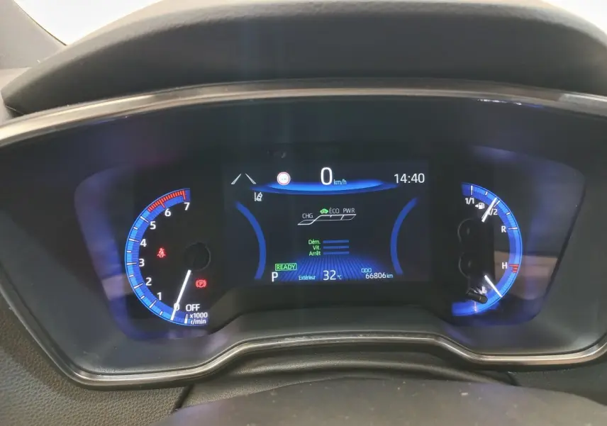 Tableau de bord numérique de la Toyota Corolla hybride 2022, affichage bleu avec compte-tours et jauge carburant.