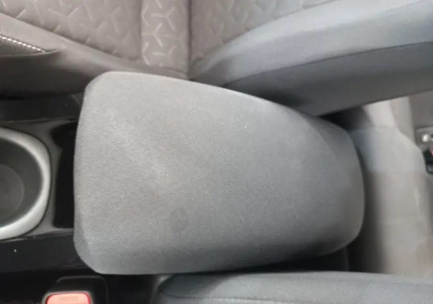 Accoudoir central en tissu gris entre les sièges avant d'une Toyota Corolla hybride 2022, vue de dessus.