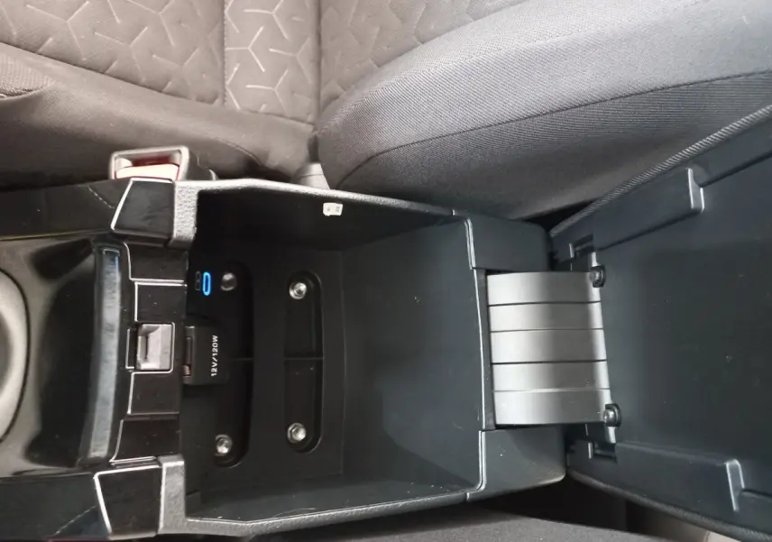 Vue rapprochée de la console centrale ouverte d'une Toyota Corolla hybride 2022, montrant un espace de rangement noir.