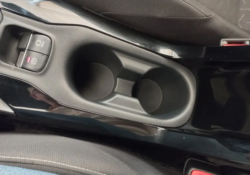 Gros plan sur la console centrale noire avec porte-gobelets et frein à main électrique de la Toyota Corolla hybride 2022.