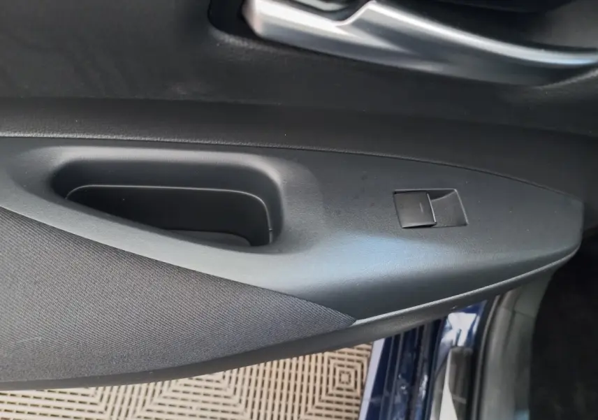 Détail de la porte côté conducteur d'une Toyota Corolla hybride bleu, avec bouton de commande de vitre.