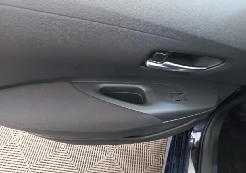 Vue rapprochée de la porte avant droite intérieure de la Toyota Corolla hybride bleu 2022 avec poignée argentée.