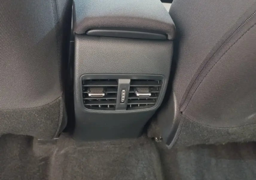 Vue rapprochée des aérateurs arrière noirs entre les sièges avant d'une Toyota Corolla hybride 2022.