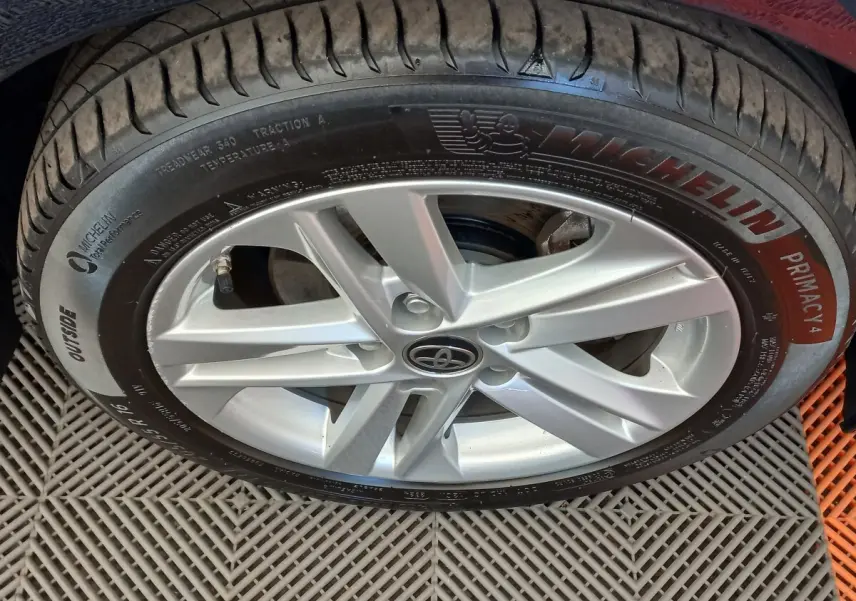 Gros plan sur la jante alliage argentée et pneu Michelin d'une Toyota Corolla hybride bleue.