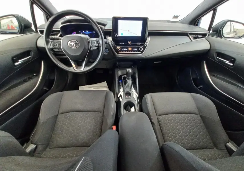 Vue intérieure avant de la Toyota Corolla hybride 2022, tableau de bord moderne avec écran tactile central et volant multifonctions cuir.