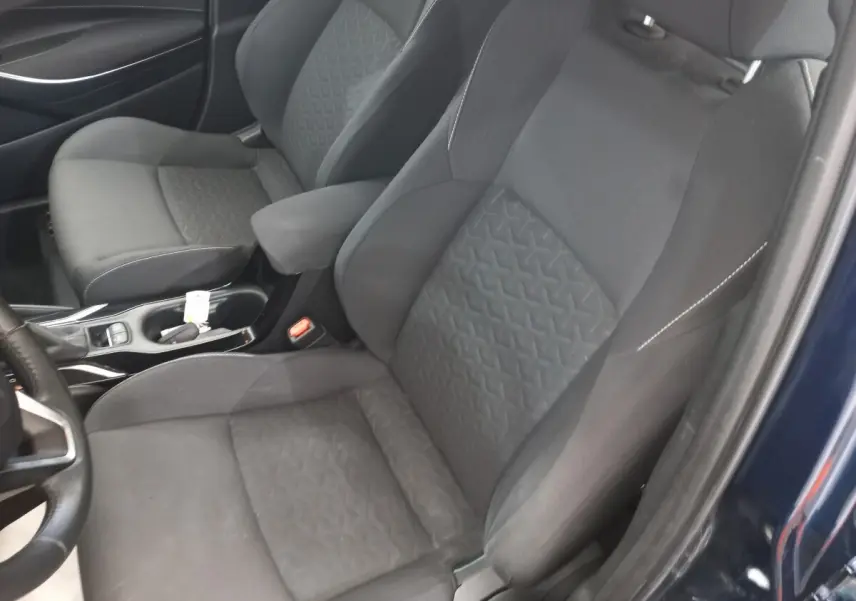 Vue intérieure rapprochée des sièges avant noirs et de l'accoudoir dans une Toyota Corolla hybride bleue 2022.