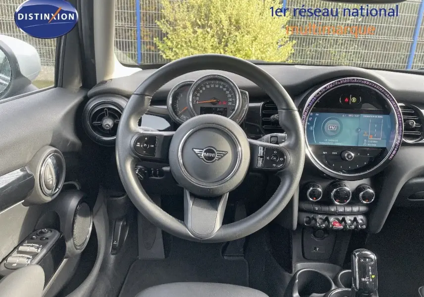 Vue intérieure centrée sur le volant et le tableau de bord de la MINI 1.5 136CH noir avec écran tactile rond et commandes au volant.
