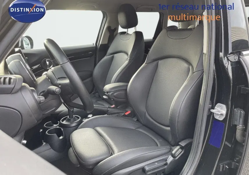 Vue intérieure côté conducteur d'une MINI 1.5 136CH noire, sièges en cuir noir avec console centrale et volant visibles.