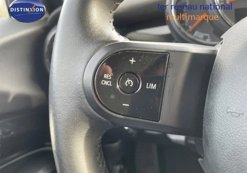 Gros plan sur le volant noir de la MINI 2023, mettant en valeur les commandes de régulateur de vitesse.