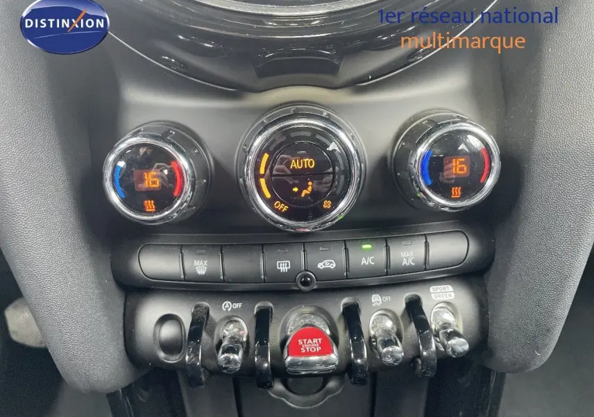 Gros plan sur la console centrale de la MINI 2023, avec commandes de climatisation et bouton start/stop rouge.