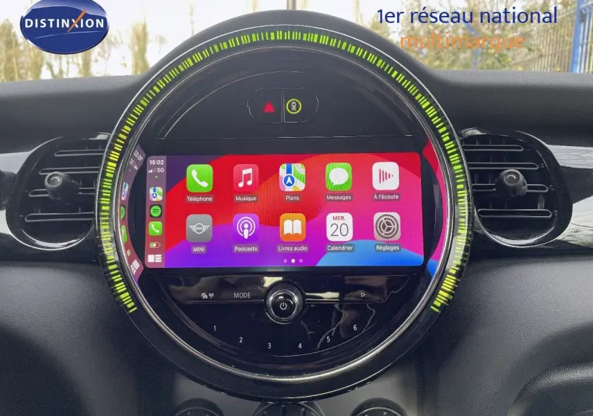 Vue rapprochée de l’écran tactile central rond du tableau de bord d’une MINI noire, avec interface Apple CarPlay affichée.