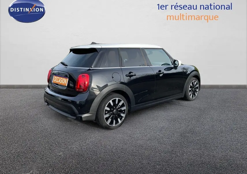 Vue 3/4 arrière droite d'une MINI noire Midnight Metal avec toit blanc et jantes bi-ton, stationnée sur sol gris.
