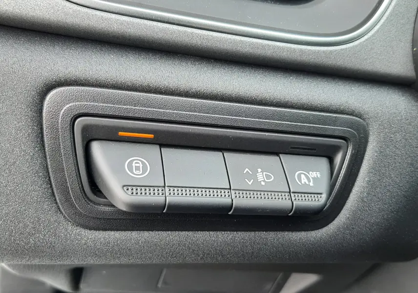 Gros plan sur les commandes noires du tableau de bord de la Renault Symbioz blanc nacré, avec témoin orange allumé.