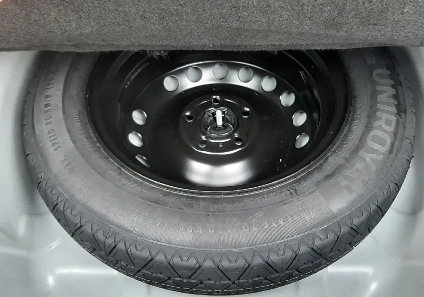 Gros plan sur la roue de secours noire Uniroyal dans le coffre d'une Renault Symbioz blanc nacré.