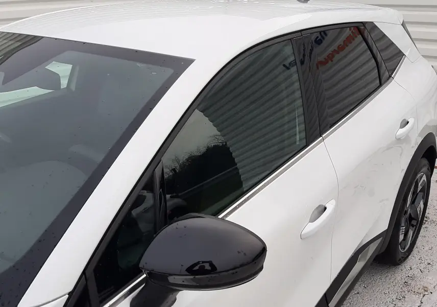 Vue 3/4 avant droit du Renault Symbioz blanc nacré, avec rétroviseur noir et vitres teintées.