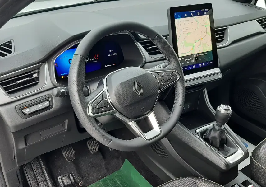 Vue intérieure côté conducteur du Renault Symbioz blanc nacré 2025, volant multifonction et écran tactile vertical avec navigation.