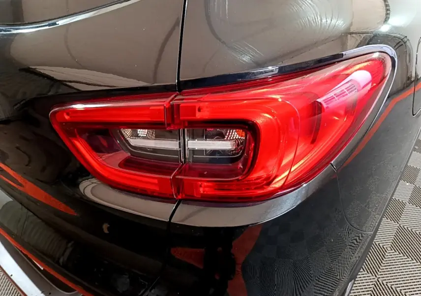 Gros plan sur le feu arrière droit rouge du Renault Kadjar Intens noir, soulignant la carrosserie brillante et les lignes arrière.
