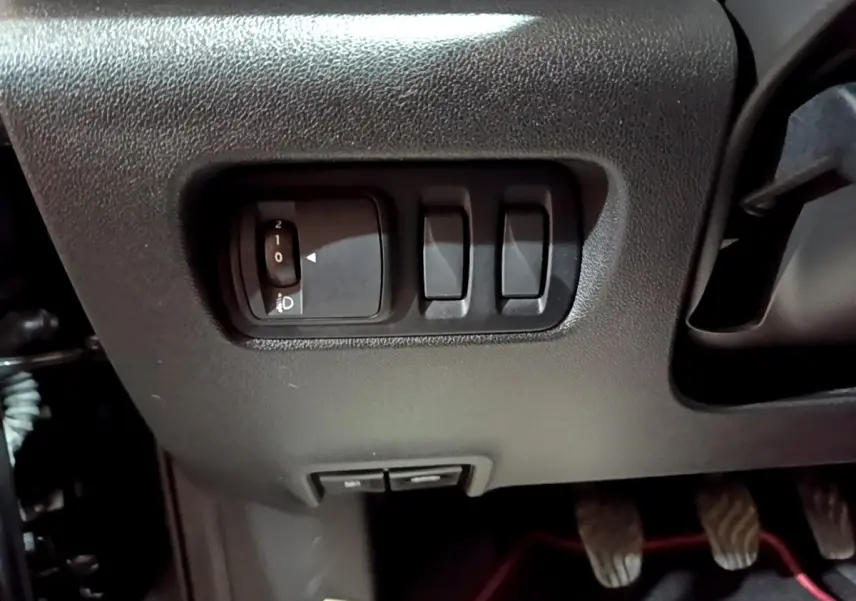 Gros plan sur les commandes d'éclairage et réglages sous le tableau de bord du Renault Kadjar noir 2018 côté conducteur.