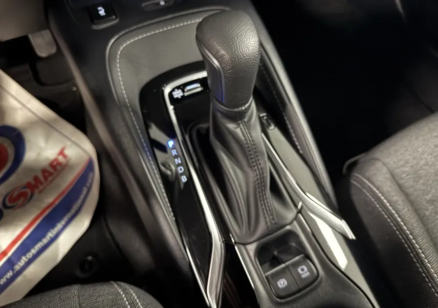 Gros plan sur la console centrale de la Suzuki Swace 2025, levier de vitesse automatique en cuir noir avec boutons électroniques.