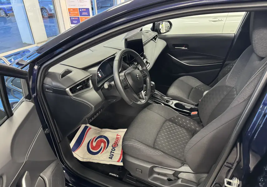 Vue intérieure côté conducteur de la Suzuki Swace bleu 2025, montrant sièges tissu et tableau de bord moderne.