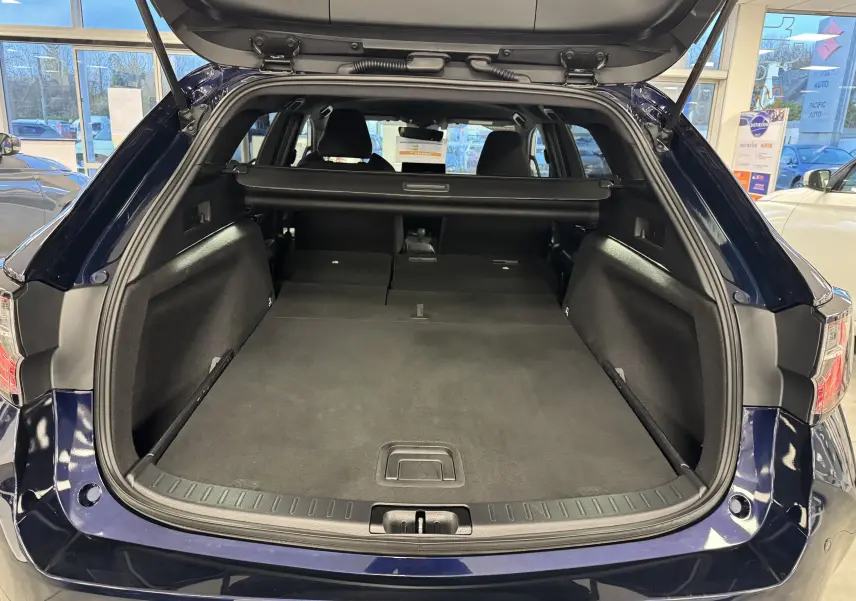 Coffre ouvert en vue arrière d’une Suzuki Swace 2025 bleu, montrant l’espace de chargement plat et la plage arrière rétractable.