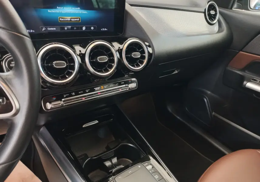 Vue intérieure côté passager du tableau de bord noir et brun du Mercedes GLA 200 Business Line avec écran tactile et aérateurs ronds.
