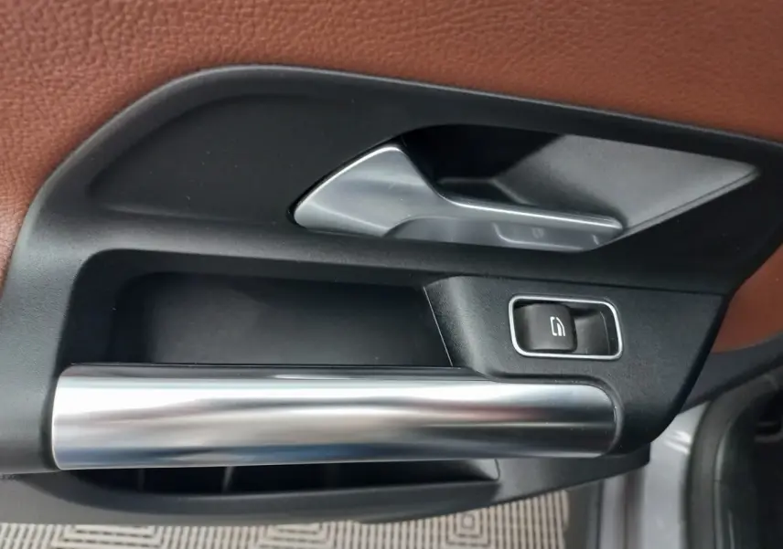 Poignée intérieure de porte avant droite en métal brossé et plastique noir sur Mercedes GLA gris foncé, 2021.