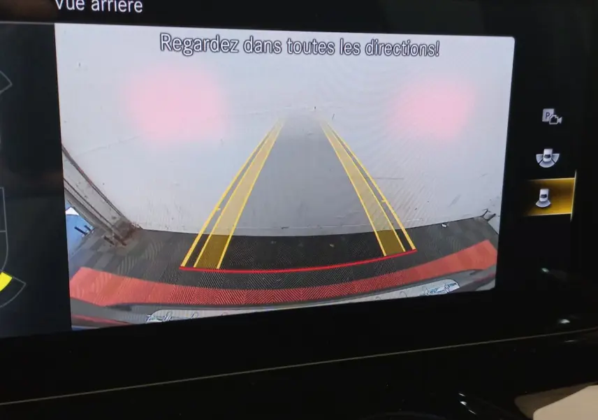 Affichage de la caméra de recul du Mercedes GLA 200 gris foncé, avec lignes de guidage jaunes et rouges visibles.