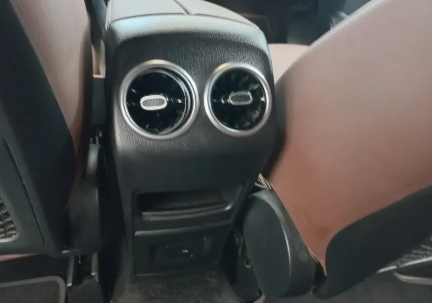 Vue rapprochée des aérateurs arrière et console centrale noire entre les sièges marron clair d’un Mercedes GLA 200.