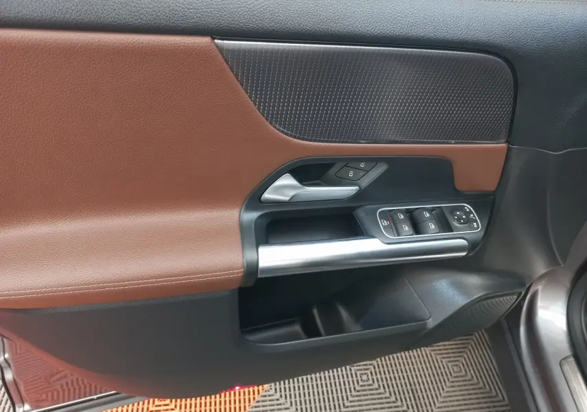 Vue rapprochée de la porte avant gauche du Mercedes GLA 200 Business Line 2021, avec garniture marron et commandes électriques.