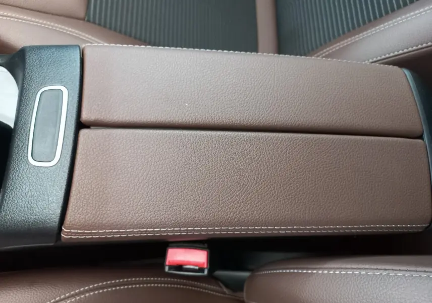 Gros plan sur l'accoudoir central en cuir marron avec surpiqûres blanches dans l'habitacle du Mercedes GLA 200.